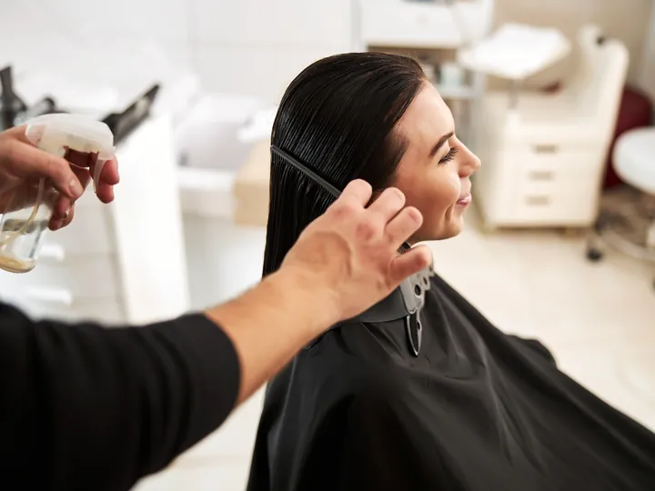 A stylist combing and setting a client's hair after a wash.