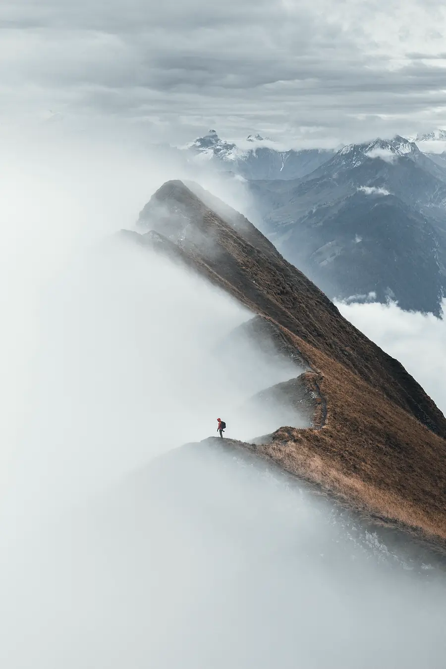 A small figure walking a ridge above the cloud.