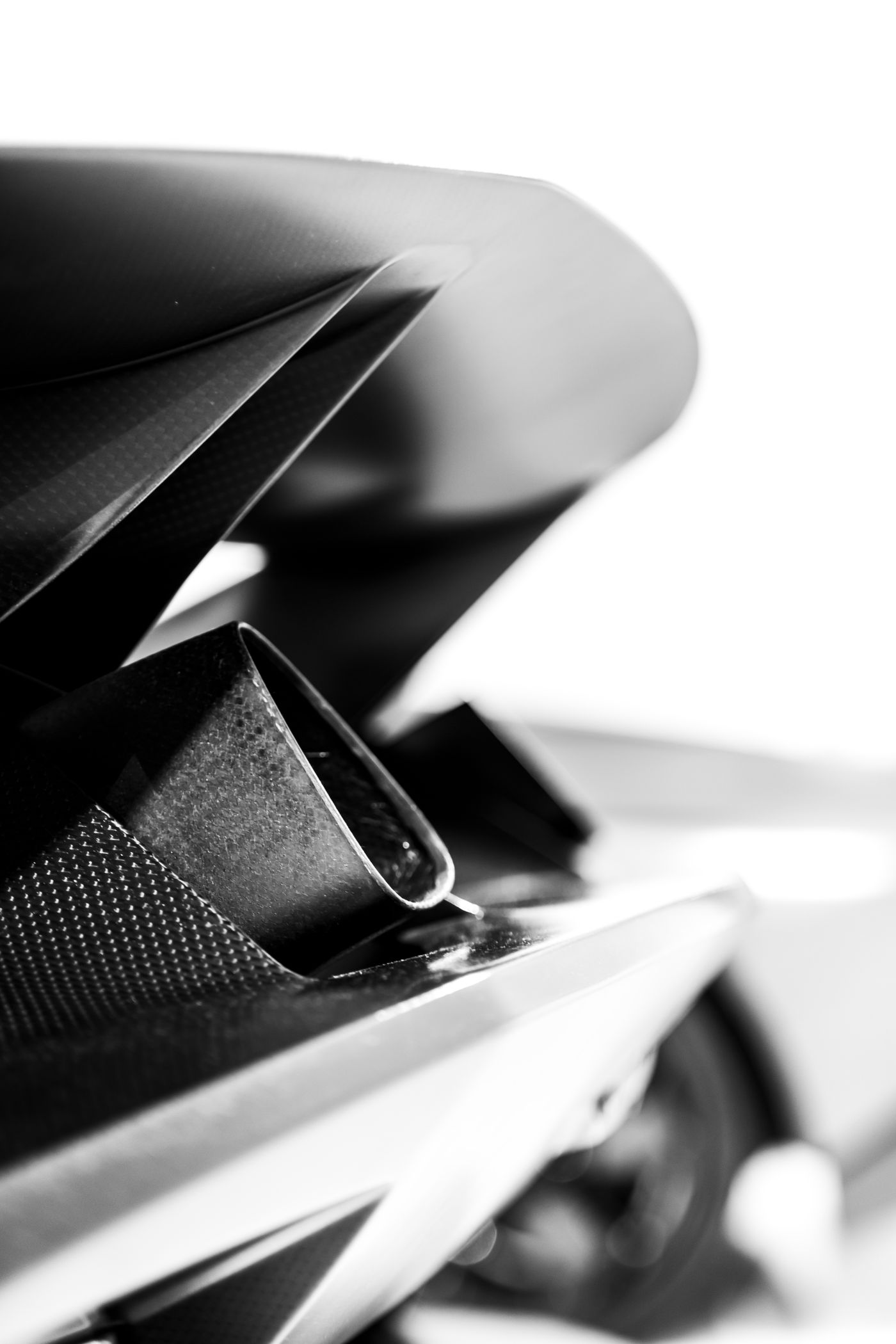 A polished exhaust tip set into a dark rear diffuser, photographed in black and white.