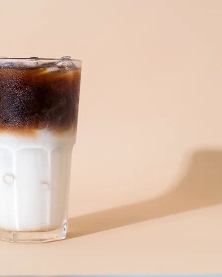 A layered iced latte in a tall glass, espresso settling through milk.