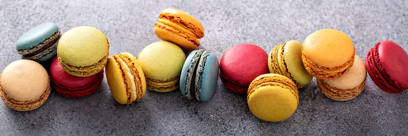 A row of thick macarons in yellow, blue, pink and orange.