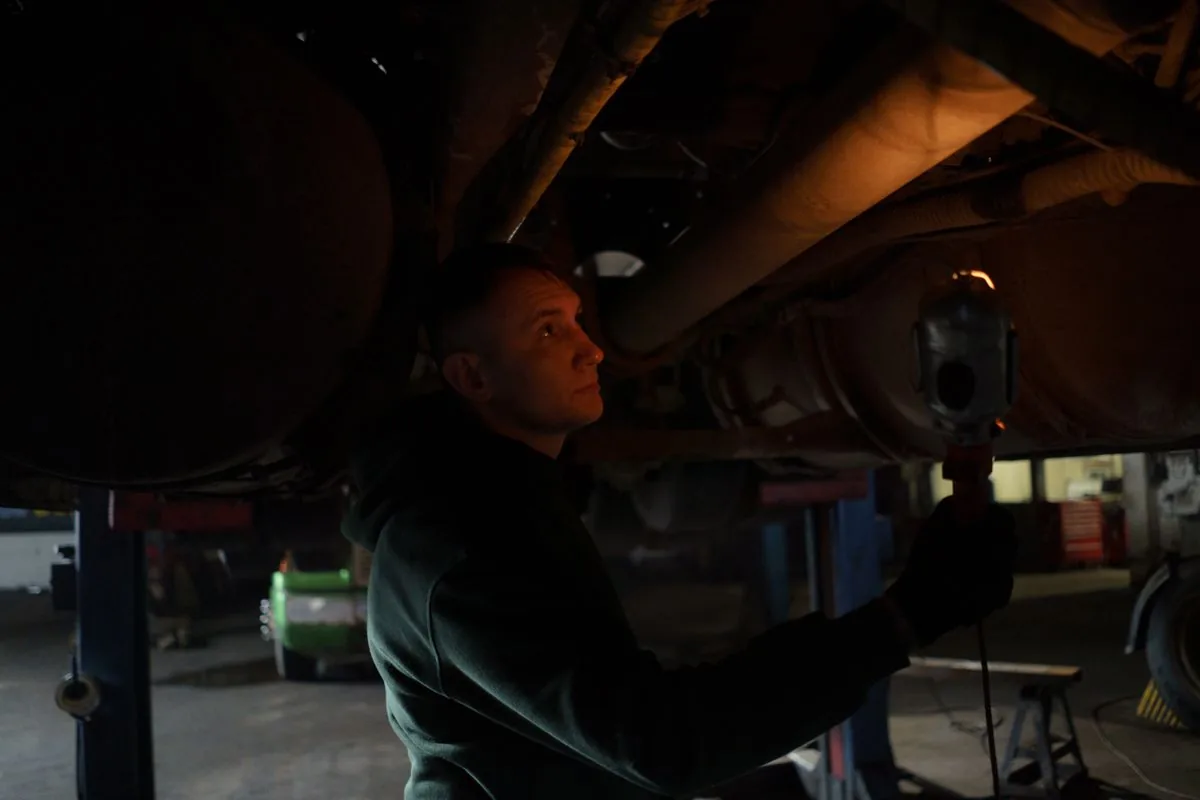 Mechanic inspecting the underbody of a car with a work light