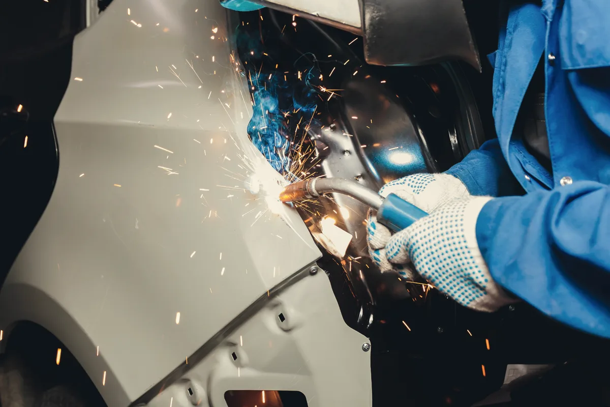 Sparks flying as a technician welds a car body panel