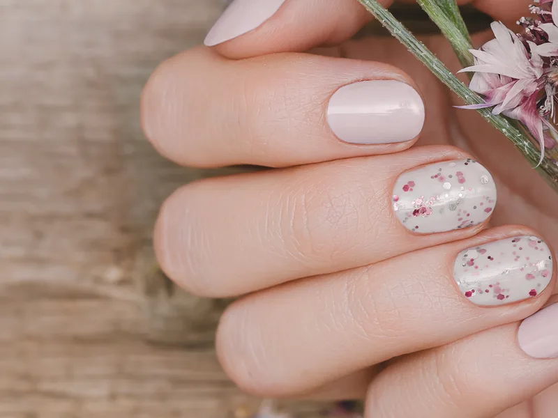 Nails with a nude base and a delicate speckled accent design.