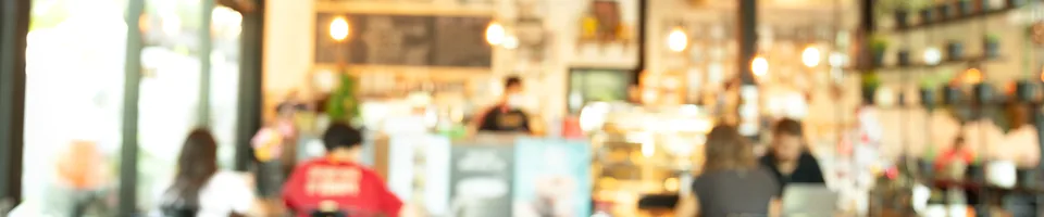 A wide view across a cafe: warm pendant lights, the counter and customers out of focus.