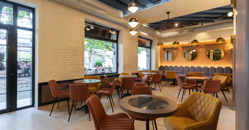 A warm cafe interior with brick-toned walls, tables and window light.