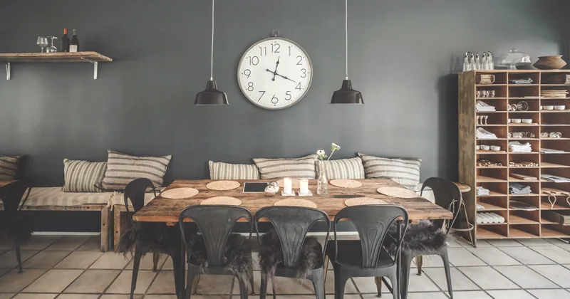 A long communal table with benches beneath pendant lights.