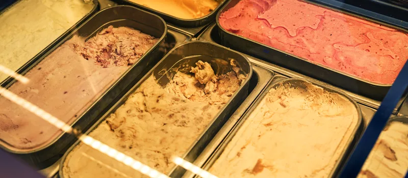 Tubs of gelato in a warm-lit display cabinet.